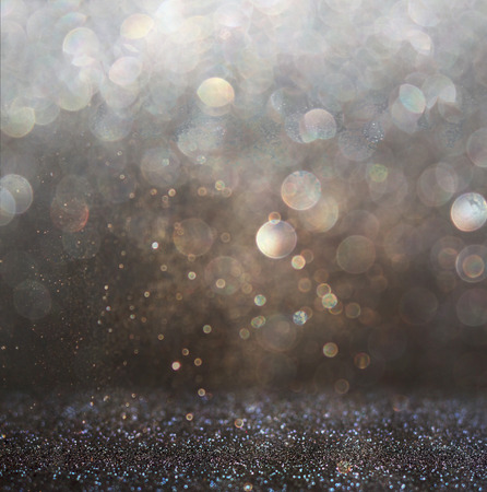 glitter vintage lights background. gold, silver, and black. de-focused.