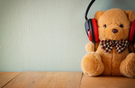 teddy bear with headphones over wooden tableの写真素材