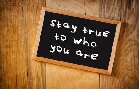 top view of blackboard with the phrase stay true to who you are, over wooden backgroundの写真素材