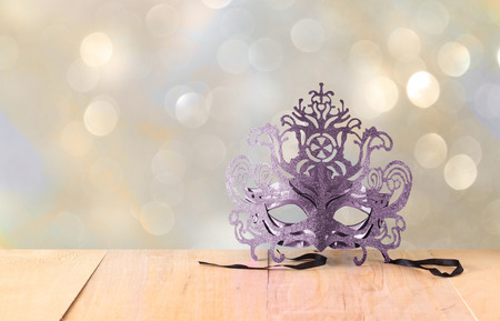 Mysterious Venetian masquerade mask on wooden table and glitter backgroundの写真素材
