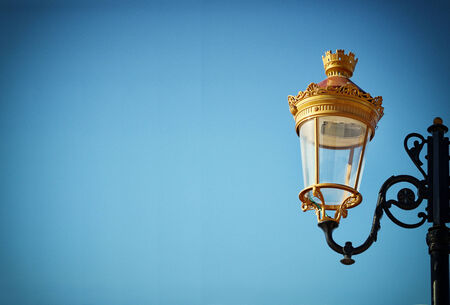 Picture of an antique street lamp against blue sky. vintage filtered image