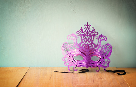 Mysterious Venetian masquerade mask on wooden table. retro filtered imageの写真素材