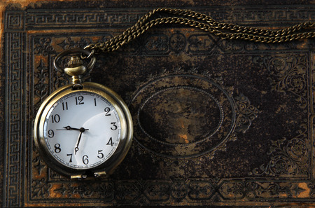 macro image of old vintage pocket watch on antique book. top view. retro filtered imageの写真素材