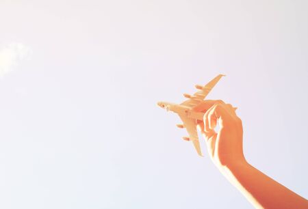 close up photo of woman hand holding toy airplane against blue sky with cloudsの写真素材