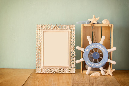 old vintage frame with naurical wheel on wooden table. vintage filtered imageの写真素材