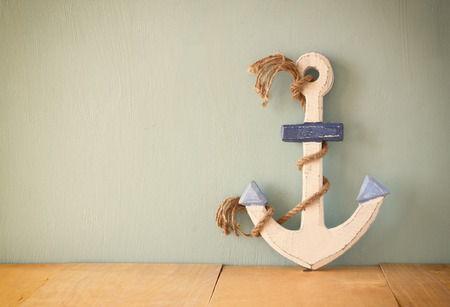 old nautical anchor on wooden table over wooden aqua backgroundの写真素材