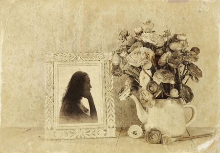 Summer bouquet of flowers and victorian frame with vintage portrait of young woman on the wooden table. black and white style image with textured overlayの写真素材
