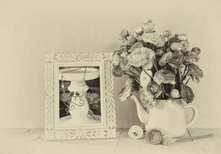 abstract photo of Summer bouquet of flowers and victorian frame with vintage frame on the wooden table. black and white style image with textured overlayの写真素材