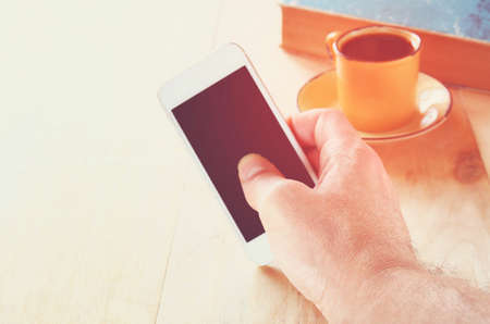 man holding smart phone over wooden table background