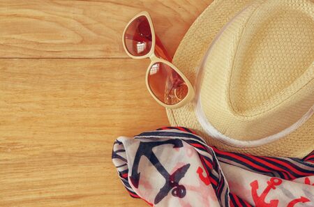 top view of stylish hat woman sunglasses and tablet fashion nautical scarf over wooden table. vacation and travel conceptの写真素材