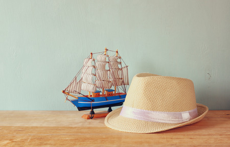 fedora hat and wooden boat over wooden table and blue background. relaxation or vacation conceptの写真素材