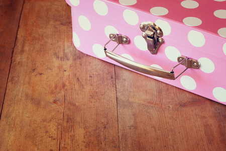 close up image of pink suitcase with polka dots over wooden tableの写真素材
