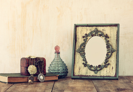 image of victorian vintage antique classical frame jewelry and perfume bottles on wooden table. filtered image