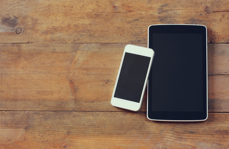 top view image of smartphone and tablet device over wooden table room for text, ready for mockup.