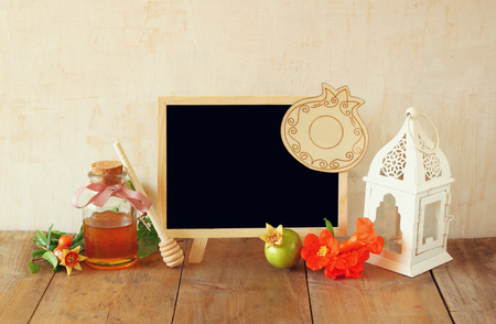 rosh hashanah jewesh holiday concept - blackboard, honey and pomegranate over wooden table. traditional holiday symbols.の写真素材