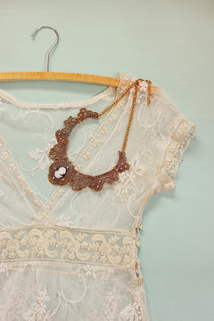 vintage white crochet lace top with antique necklace on wooden backgroundの写真素材