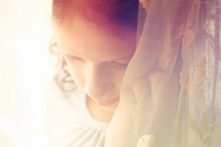 abstract portrait of thoughtful little girl near window. retro filtered imageの写真素材