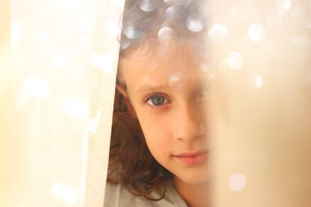 abstract portrait of thoughtful little girl near window. retro filtered imageの写真素材