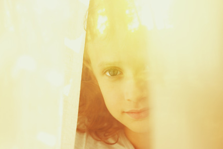 abstract portrait of thoughtful little girl near window. retro filtered imageの写真素材