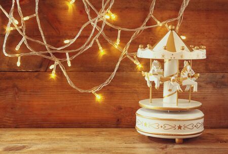 old vintage white carousel horses with garland gold lights on wooden table. retro filtered imageの写真素材