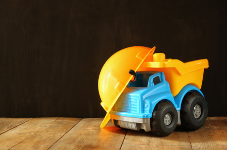 Dump truck toy and safety hat over wooden textured backgroundの写真素材