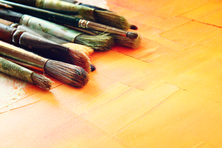 top view of set of used paint brushes over wooden tableの写真素材