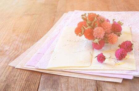 selective focus image of dry flowers and hand made vintage letters paper on wooden table. retro filtered imageの写真素材