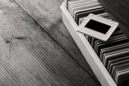 black and white close up image of old slides frames and old camera over wooden tableの写真素材