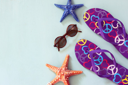 colorful flip flops, starfish, shells and sunglasses on wooden backgroundの写真素材