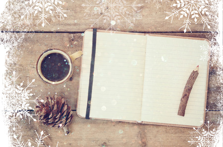 top image of open notebook with blank pages, next to pine cones and cup of coffee over wooden table. top image, glitter overly with snowflakesの写真素材