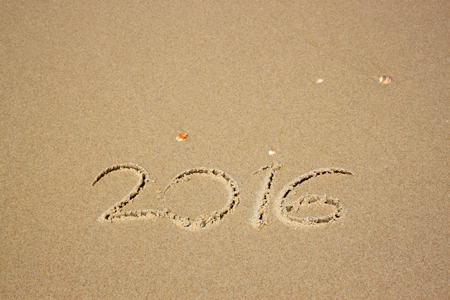 new year 2016 written in sandy beach. image is retro filtered