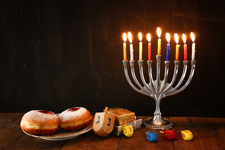 image of jewish holiday Hanukkah with menorah traditional Candelabra, donuts and wooden dreidels spinning top. retro filtered imageの写真素材