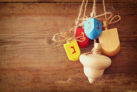 image of jewish holiday Hanukkah with wooden colorful dreidels spinning top hanging on a rope over wooden backgroundの写真素材