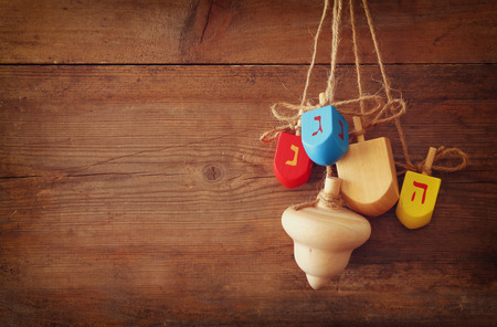 image of jewish holiday Hanukkah with wooden colorful dreidels spinning top hanging on a rope over wooden backgroundの写真素材