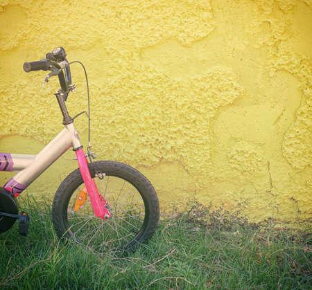 kid bicycle next to yellow textured wallの写真素材