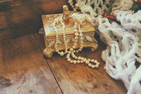 A beautiful antique golden jewelry box with natural white pearls on wooden table. retro filtered imageの写真素材