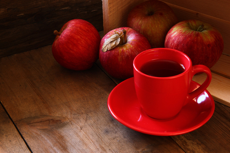 red cup of cider and red apples on wooden old table. retro filtered imageの写真素材