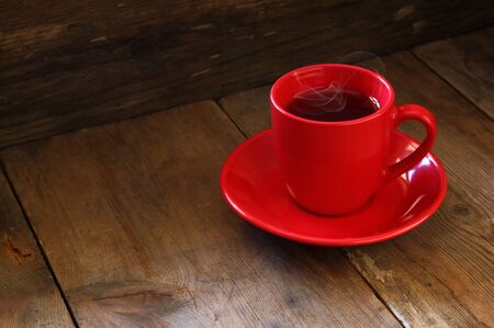 red cup of tea on wooden old table. retro filtered imageの写真素材