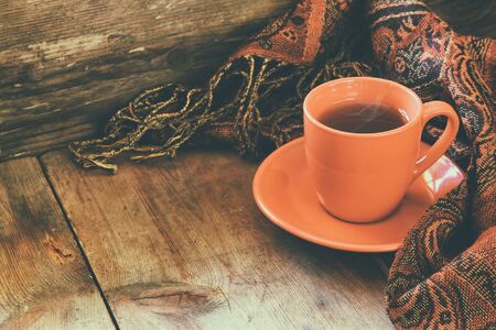 Cup of tea with fashion scarf on wooden tableの写真素材