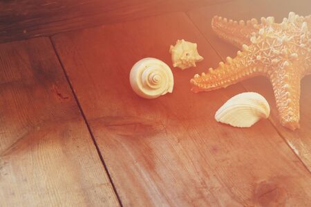 photo of vintage decorative boat, sea shells and starfish on wooden old table. retro filtered image. marine backgroundの写真素材