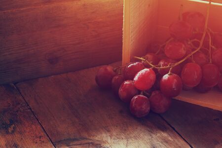 low key image of red grapes over wooden textured tableの写真素材