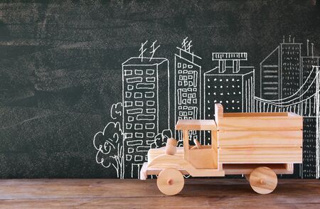 photo of wooden toy truck in front of chaklboard with city illustration.の写真素材