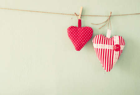 image of fabric hearts hanging on rope in front of wooden background. retro filteredの写真素材