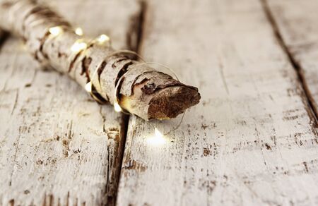old tree log with fairy christmas lights on wooden table.selective focus.の写真素材