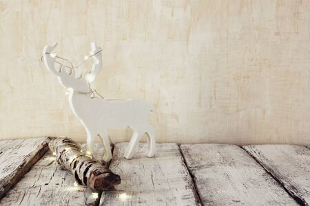 old tree log with fairy christmas lights and reindeer on wooden table.selective focusの写真素材