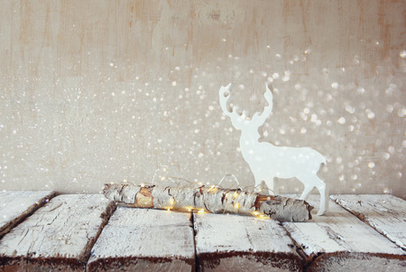 old tree log with fairy christmas lights and reindeer on wooden table.selective focusの写真素材