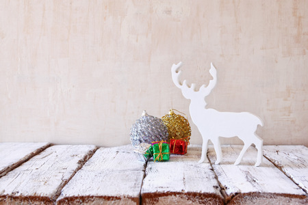 image of christmas decorations and white raindeer in front of white wooden backgroundの写真素材