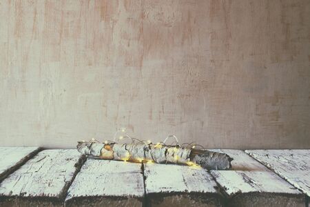 old tree log with fairy christmas lights on wooden table.selective focus.の写真素材