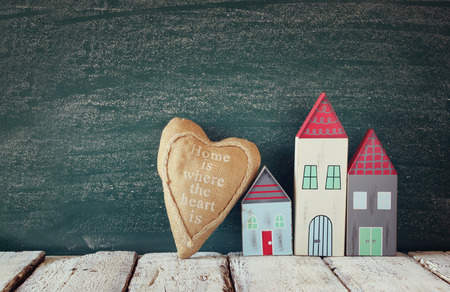 image of vintage wooden colorful houses and fabric heart on wooden table in front of blackboardの写真素材