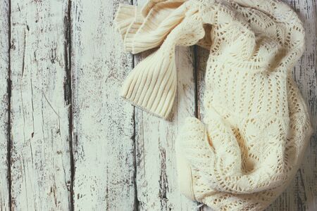 top view image of white cozy knitted sweater on a wooden table. faded retro style imageの写真素材